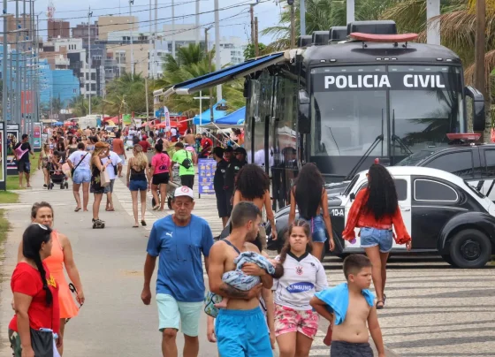 Avenida movimentada com muitas pessoas durante um evento, com policiamento visível e atividades ao ar livre, destacando a presença da Polícia Civil. Delegacia Móvel da PCPR é ponto de referência nos eventos do Verão Maior Paraná