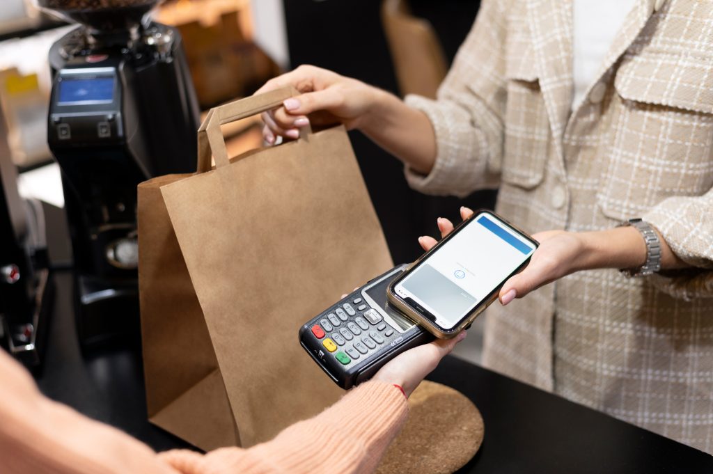 Imagem mostra pessoa usando o smartphone para pagar comprar; comércio, varejo