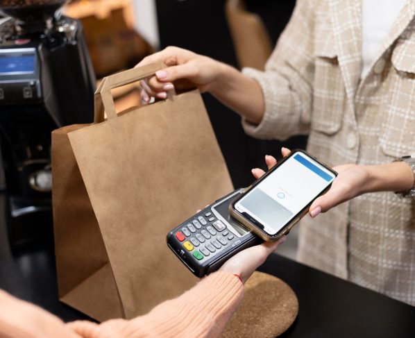 Imagem mostra pessoa usando o smartphone para pagar comprar; comércio, varejo